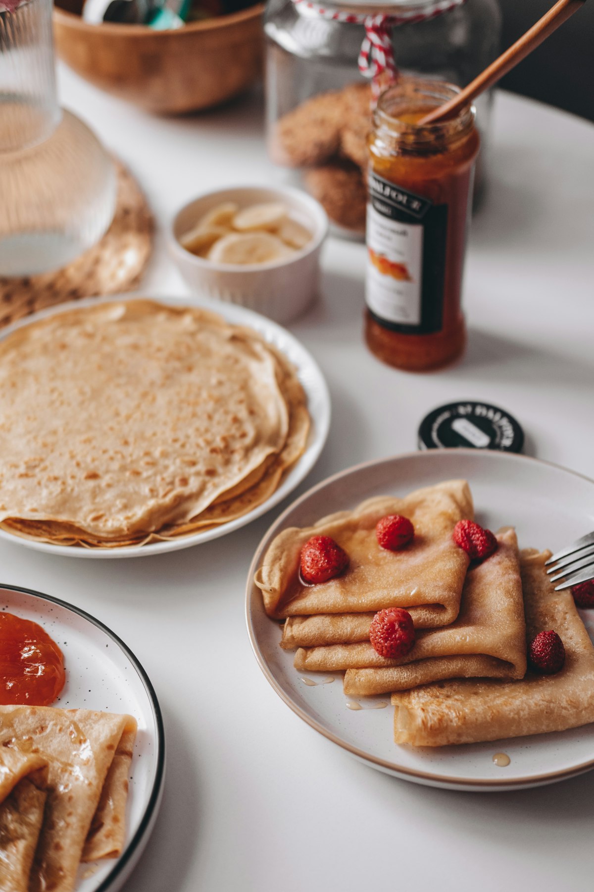 Gedeckter Tisch mit frischen Crêpes, Marmelade und Früchten